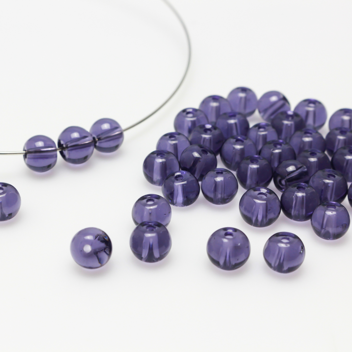 6mm round glass beads that are a transparent purple color.