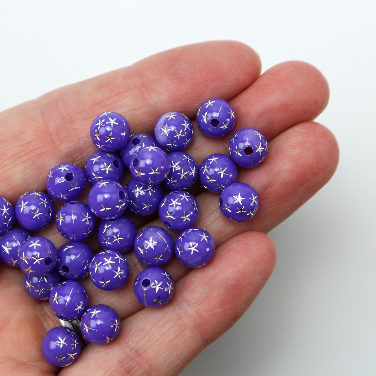 8mm round purple opaque beads that have a silver star design etched into them.