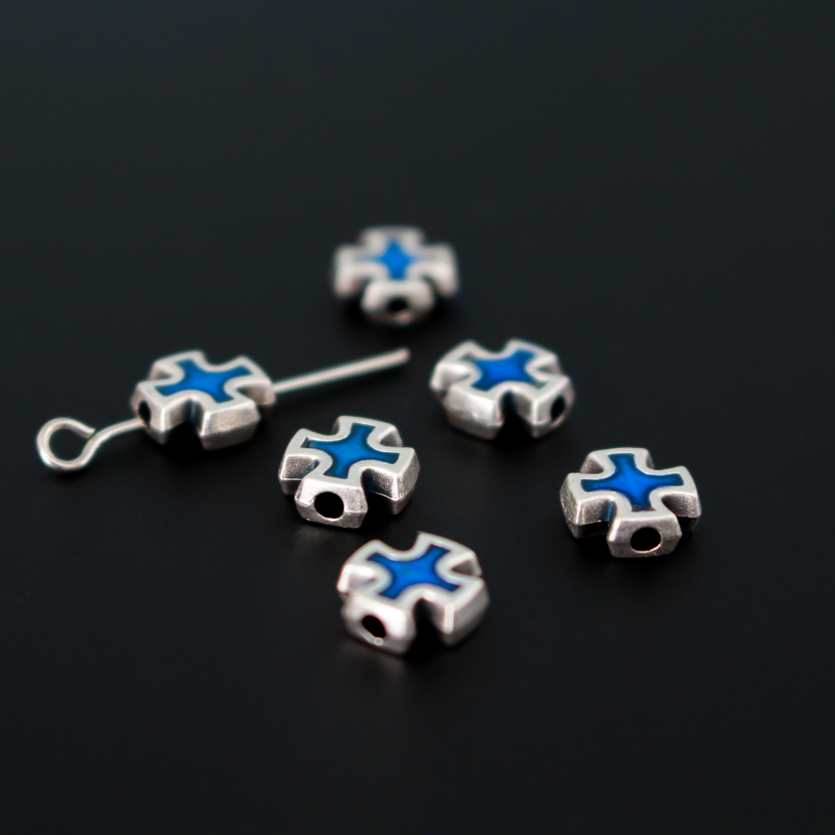 Cross shaped beads that are accented with blue enamel on both sides.