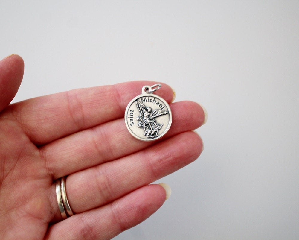 womans hand holding catholic patron saint michael medal