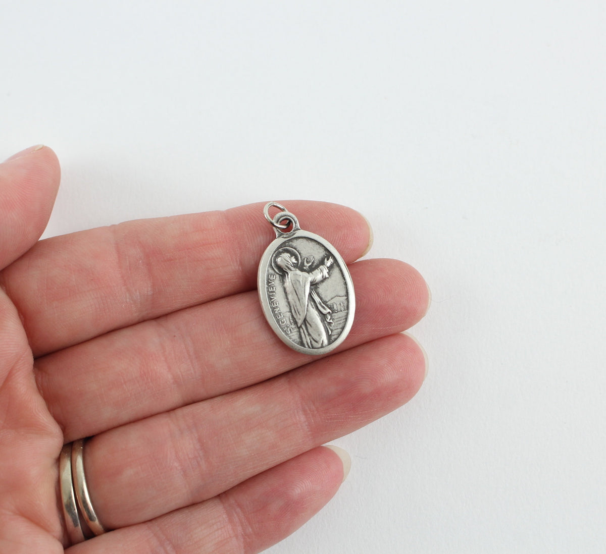 womans hand holding catholic patron saint medal