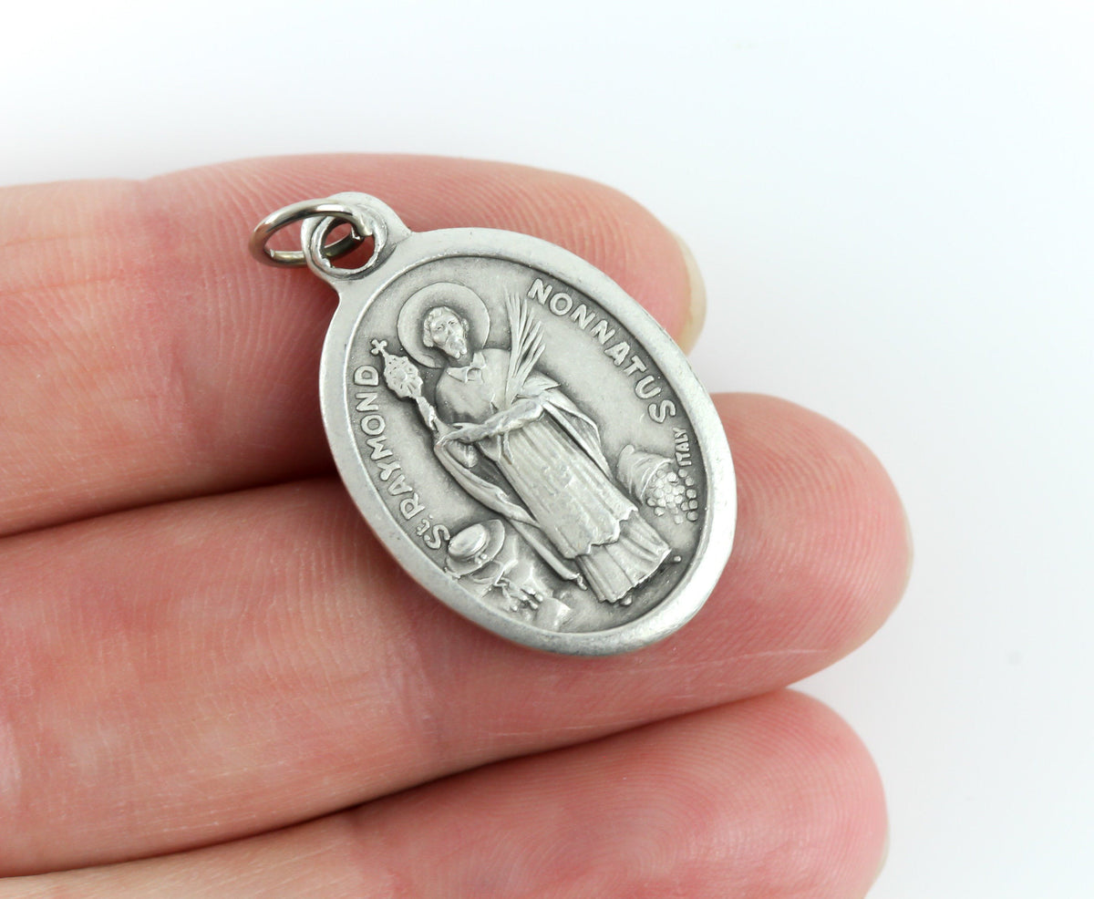 womans hand holding catholic patron saint medal