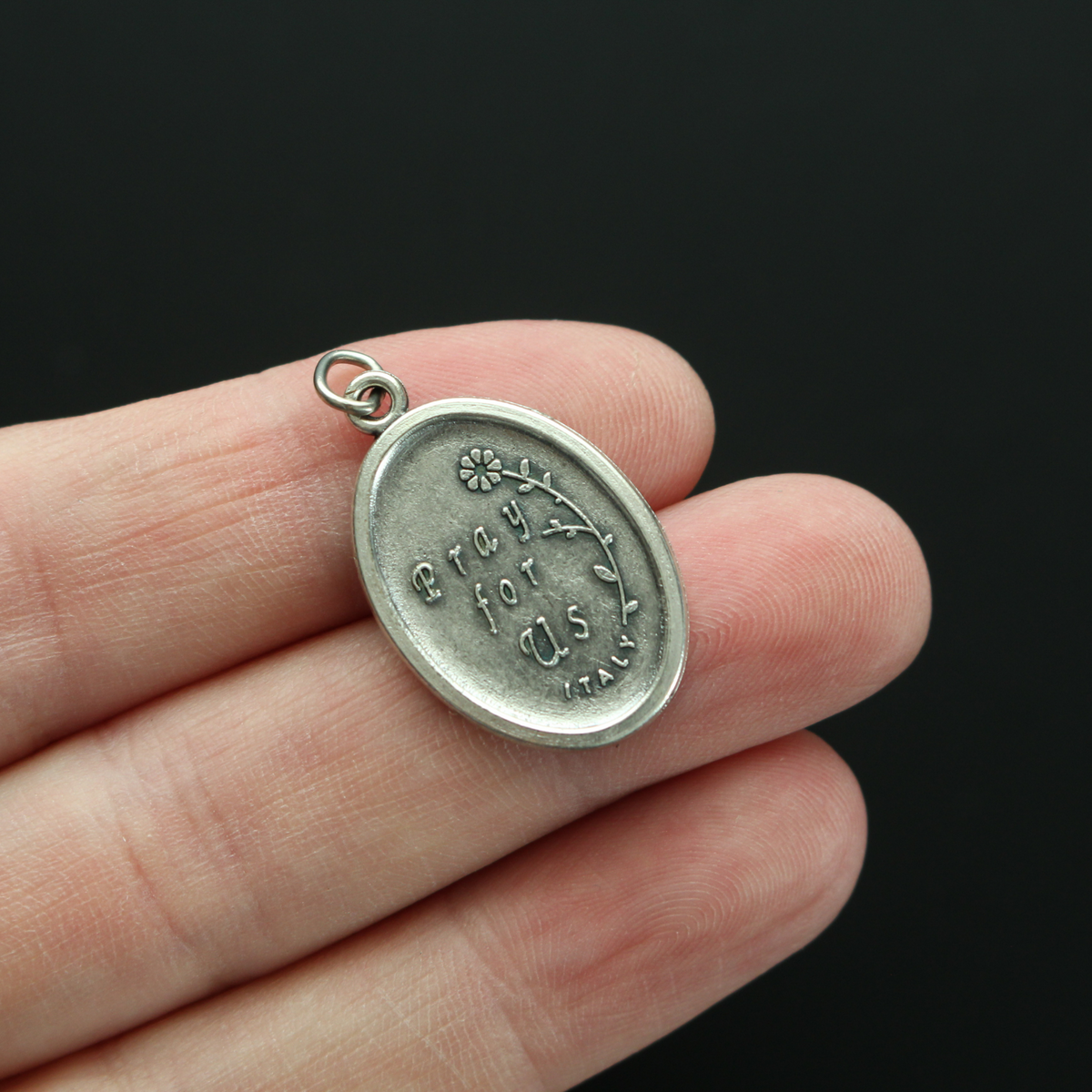 Saint Gerard Majella medal that depicts the saint holding a cross on the front and "Pray For Us" on the back