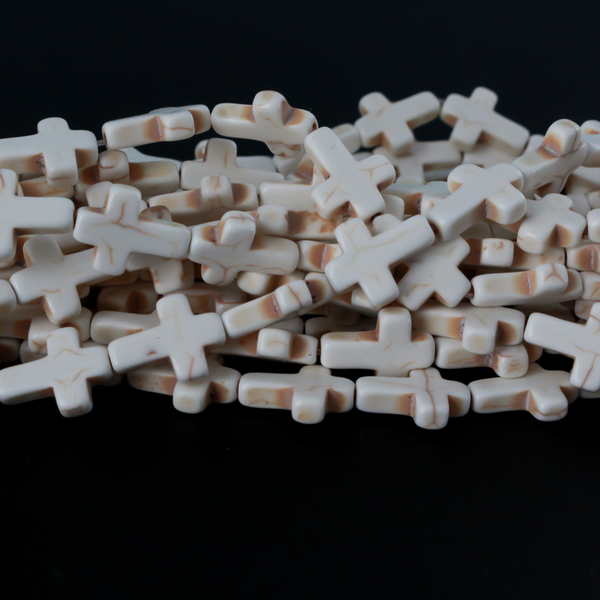Beige cross shaped beads that are a synthetic turquoise material dyed an off-white beige color. Sold by the strand