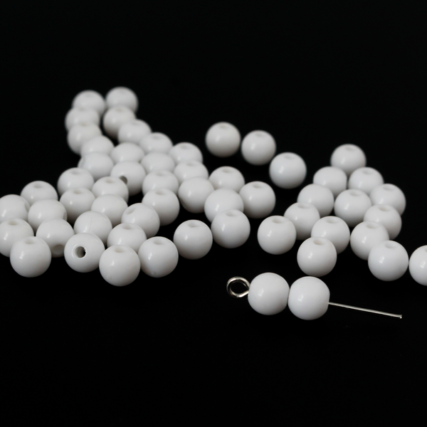 Round white opaque beads that are 6mm in diameter with a 1mm hole siz