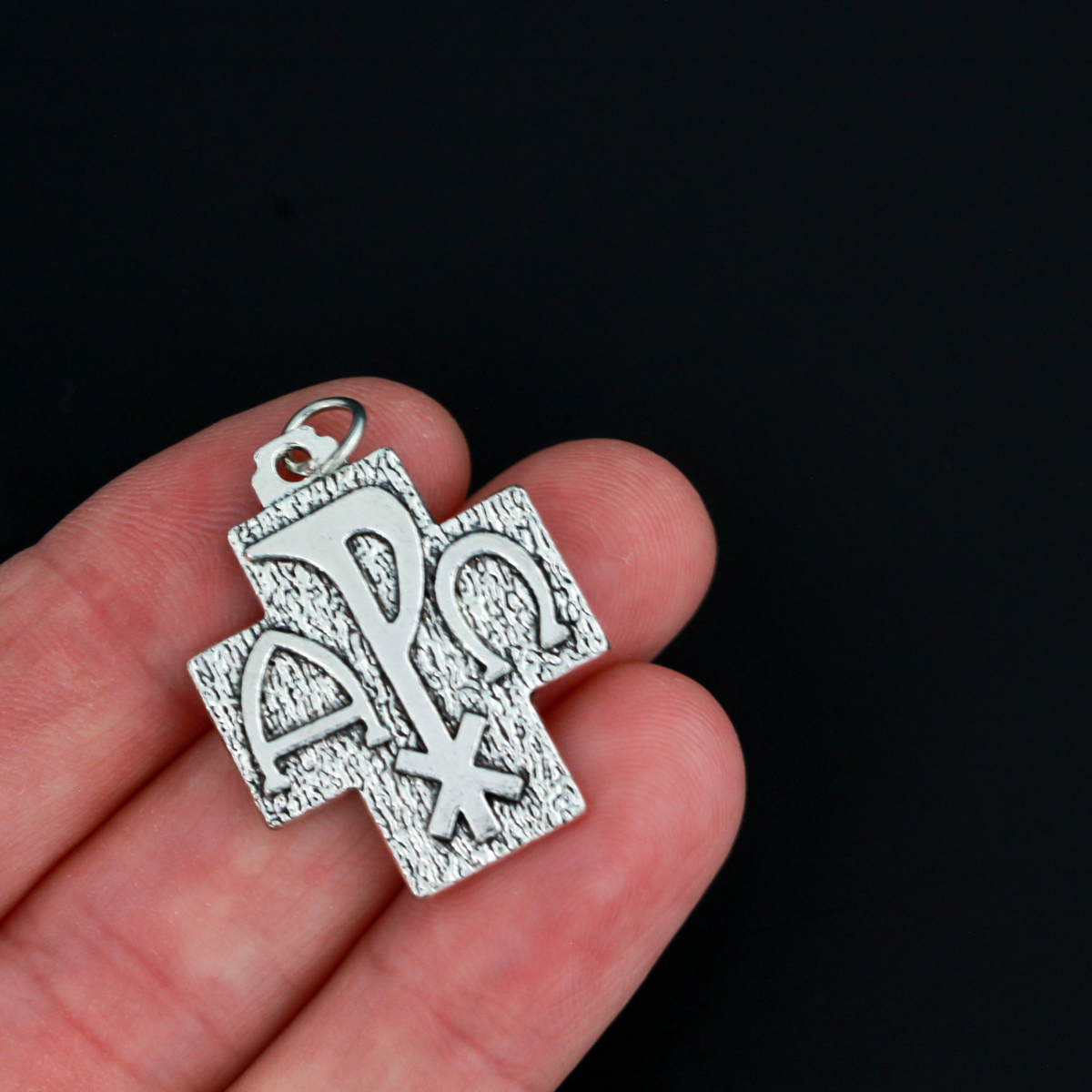 Alpha Omega Chi-rho cross charms that feature the symbols for alpha, omega, and Christ on the front. The backside is textured.