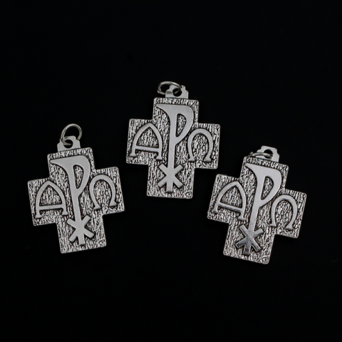 Alpha Omega Chi-rho cross charms that feature the symbols for alpha, omega, and Christ on the front. The backside is textured.