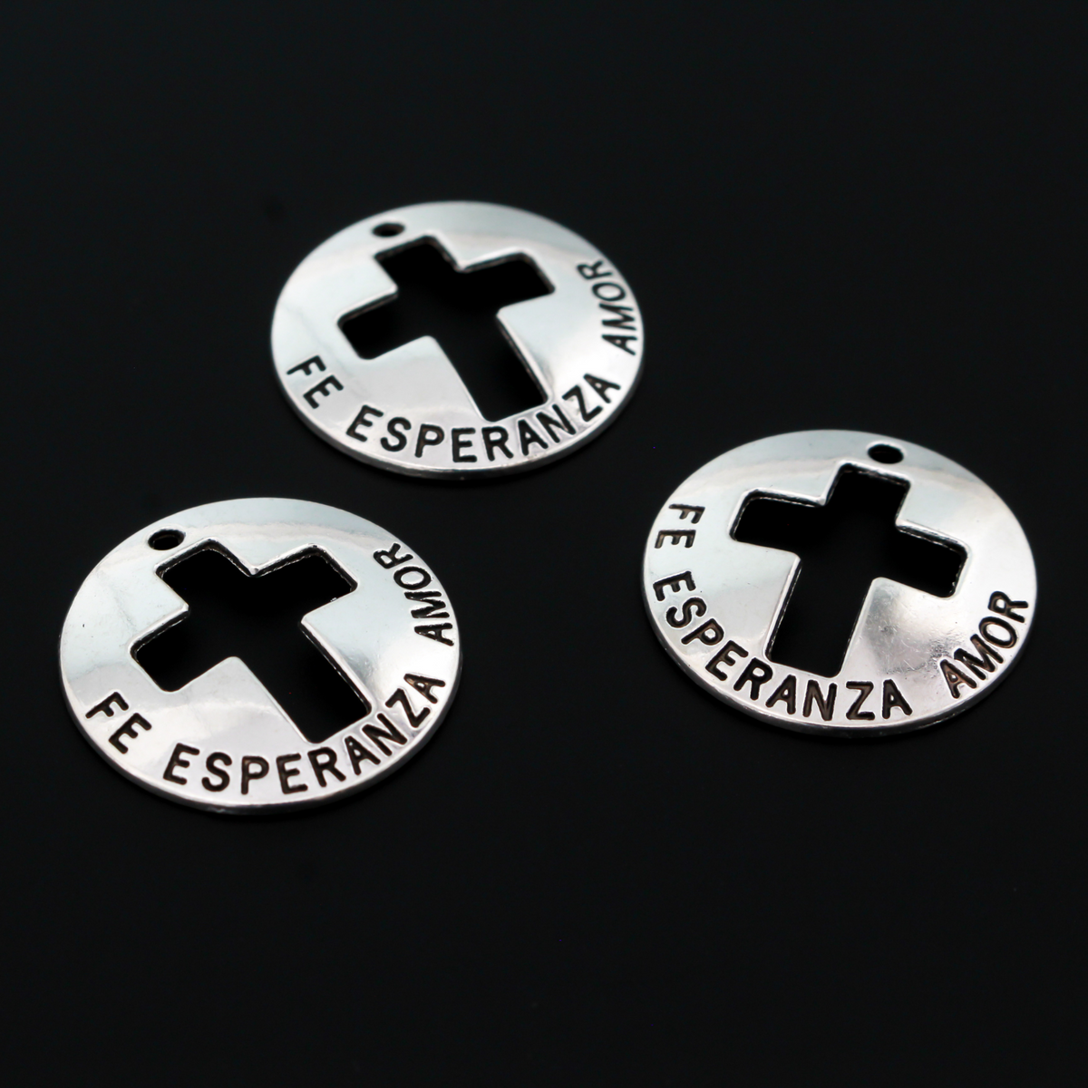 Fe, Esperanza, Amor - Spanish for Faith, Hope, Love. These charms are round with a slight curve and a cut out cross in the center