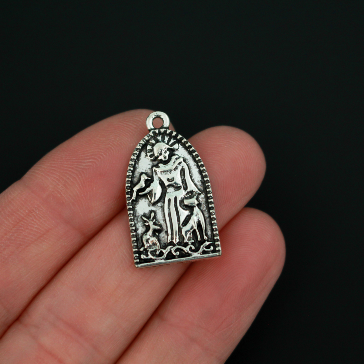 Saint Francis of Assisi charms depicting the saint with animals. The charm has an arched grotto style shape