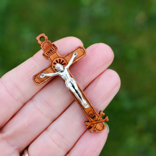 The cross is made of genuine olive wood and the body of Christ is a zamac base alloy with genuine oxidized silver-plating. There is a cutout starburst design behind the head of Jesus and the Golgotha skull at the base of the cross.