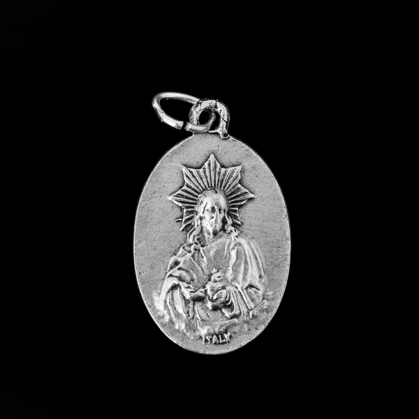 Our Lady of Montserrat medal that depicts Mary on the front and the Sacred Heart of Jesus on the back