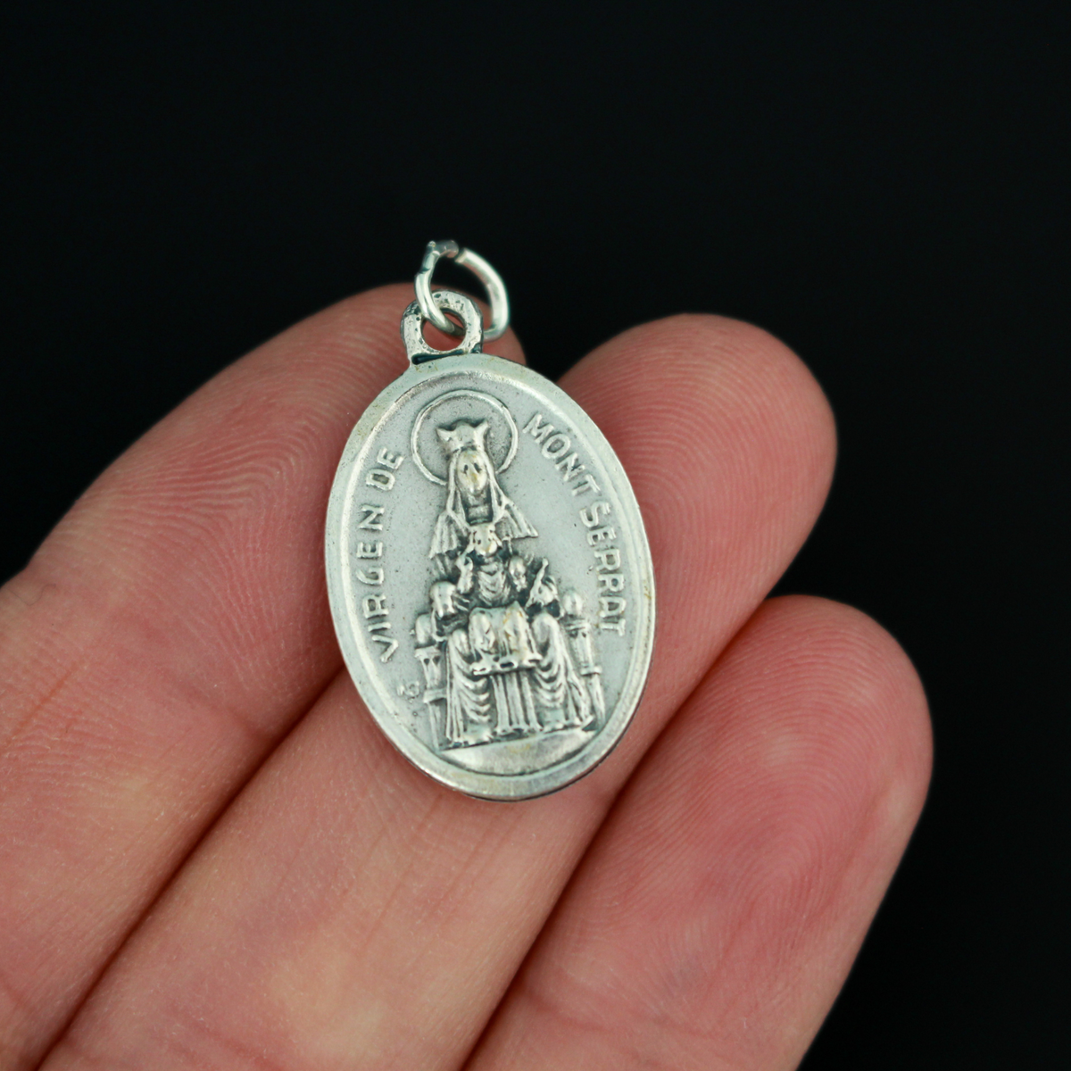 Our Lady of Montserrat medal that depicts Mary on the front and the Sacred Heart of Jesus on the back