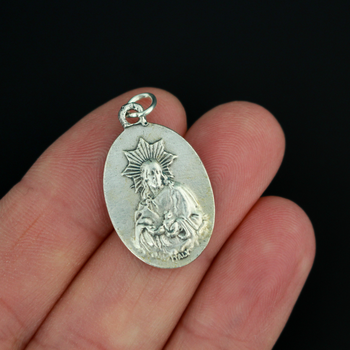 Our Lady of Montserrat medal that depicts Mary on the front and the Sacred Heart of Jesus on the back