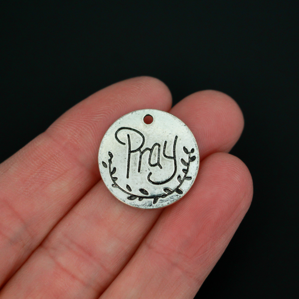 Flat, 20mm round charms engraved with the word "PRAY" with an olive branch detail beneath