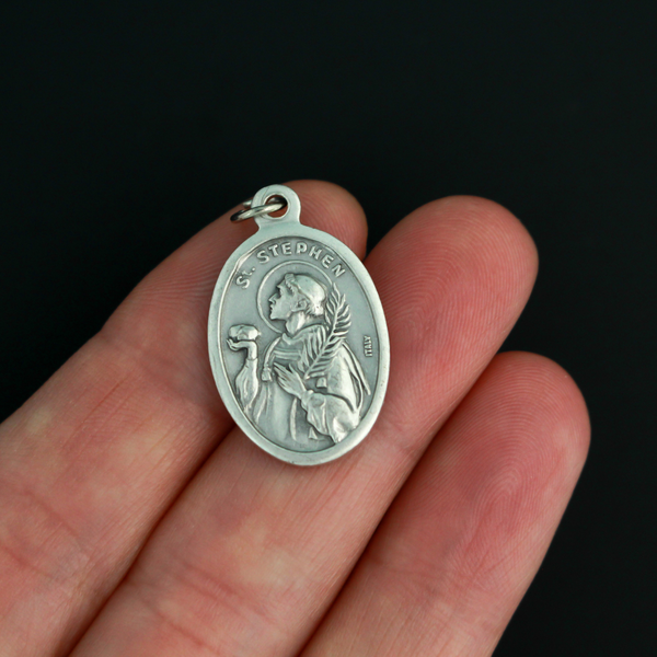 Saint Stephen oval medal that depicts the saint holding a rock on the front and "Pray For Us" on the back