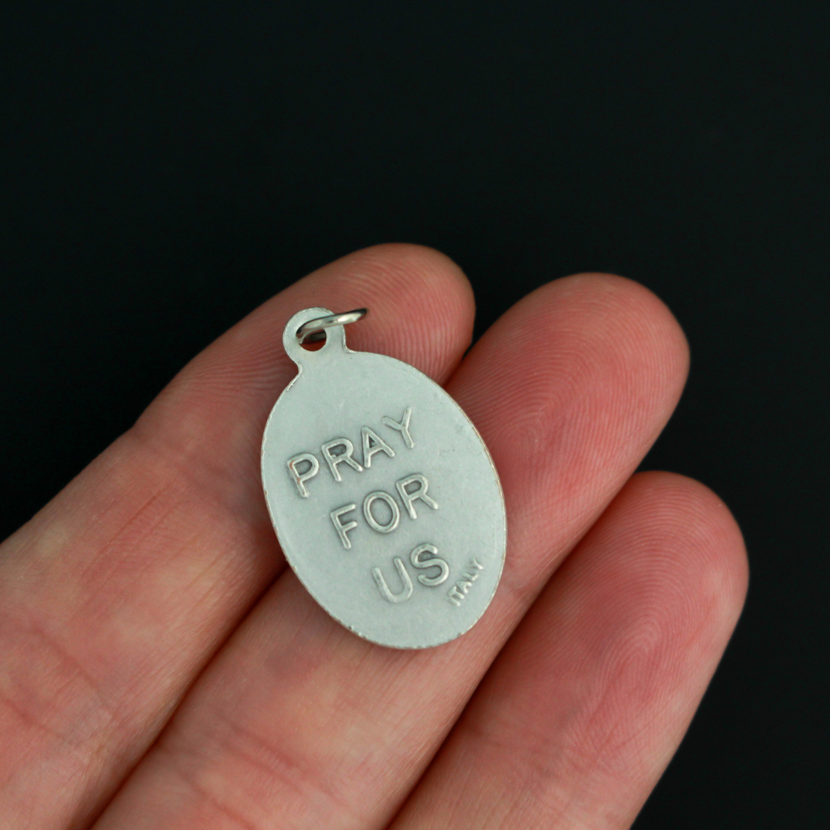 Saint Stephen oval medal that depicts the saint holding a rock on the front and "Pray For Us" on the back