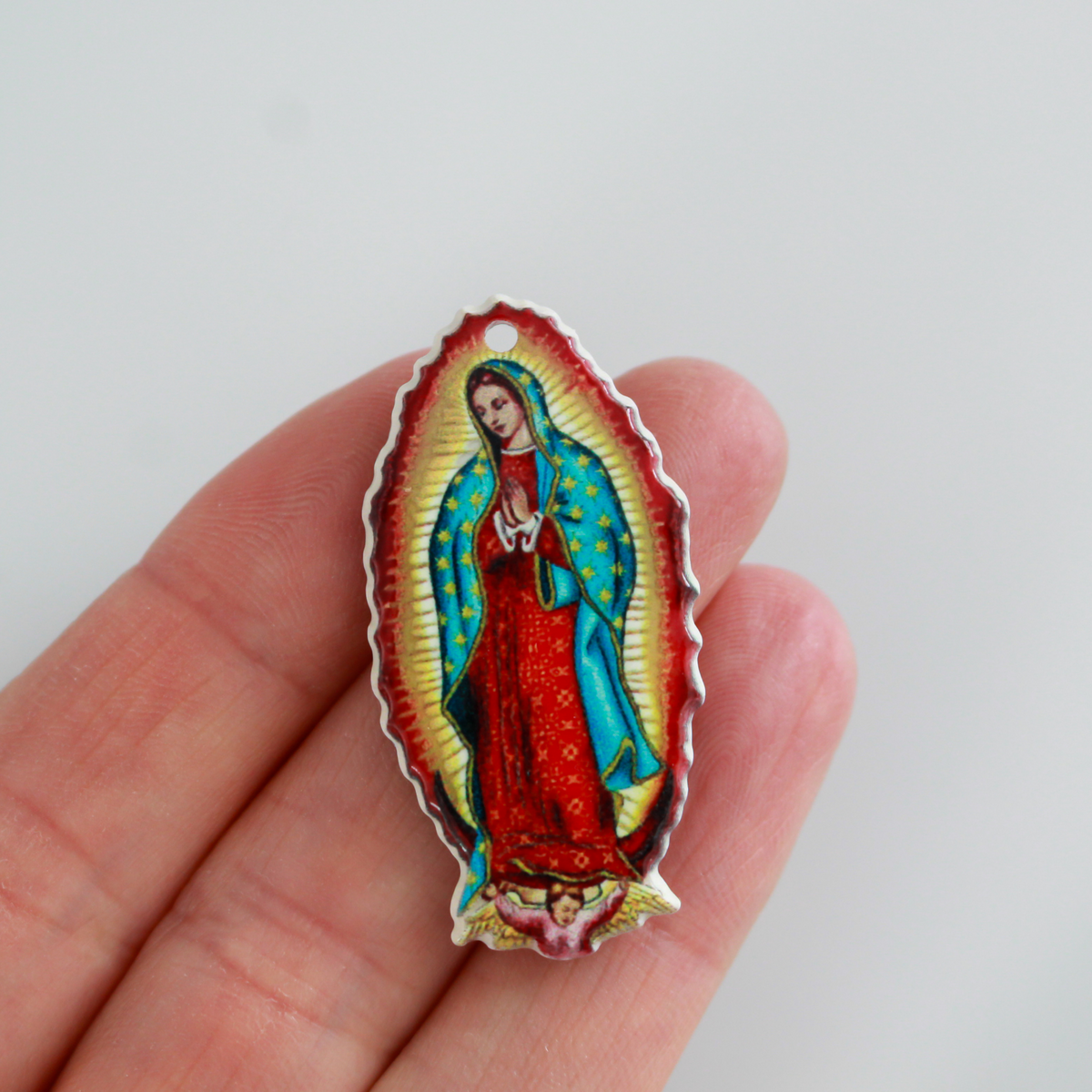 crylic pendants with a printed full color image of Our Lady of Guadalupe. The image is reversed on the backside