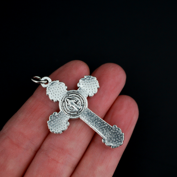 ornate crucifix crosses in an antiqued silver-tone color with the medal of Saint Benedict behind Jesus