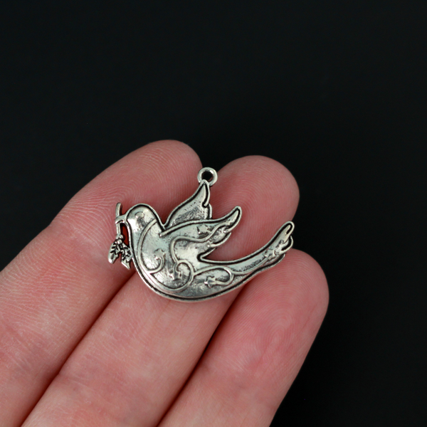 silver tone dove charm carrying an olive branch which is a symbol of peace, 28mm x 22mm