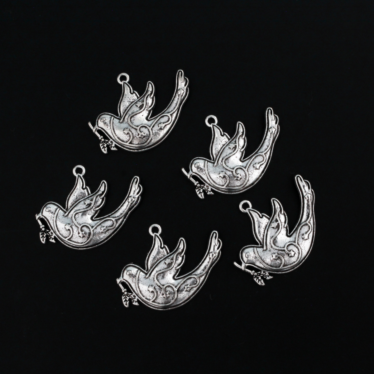 silver tone dove charm carrying an olive branch which is a symbol of peace, 28mm x 22mm