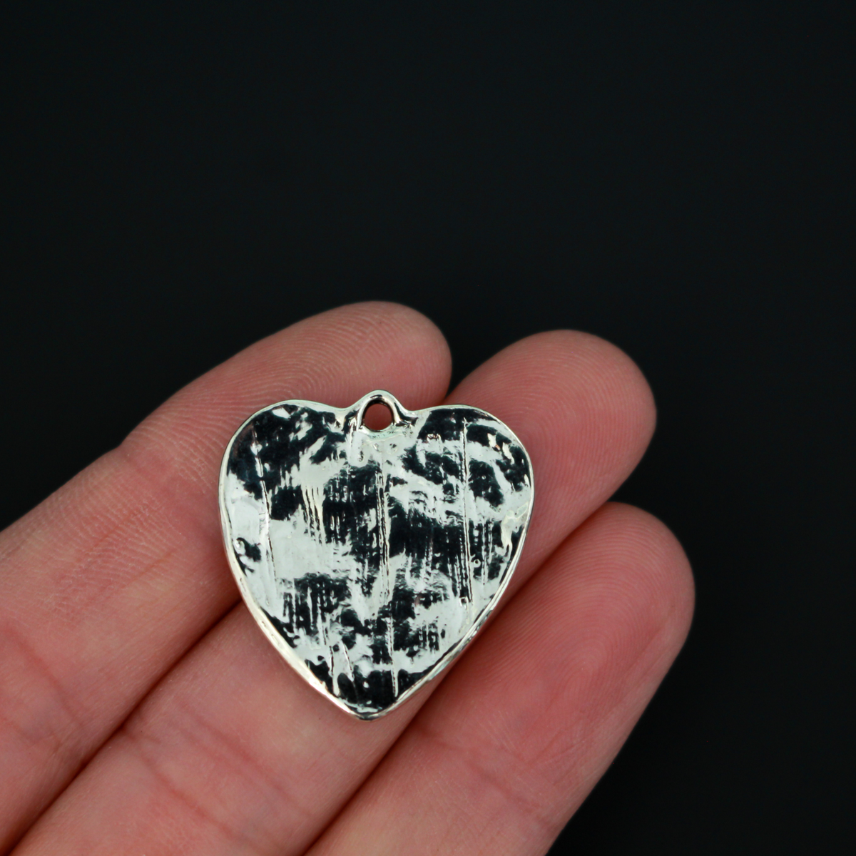 Shiny silver heart charms engraved with a bible passage from First Corinthians 13:13 “And now these three remain: faith, hope and love. But the greatest of these is love." The backside of the charm is blank with a pattern.