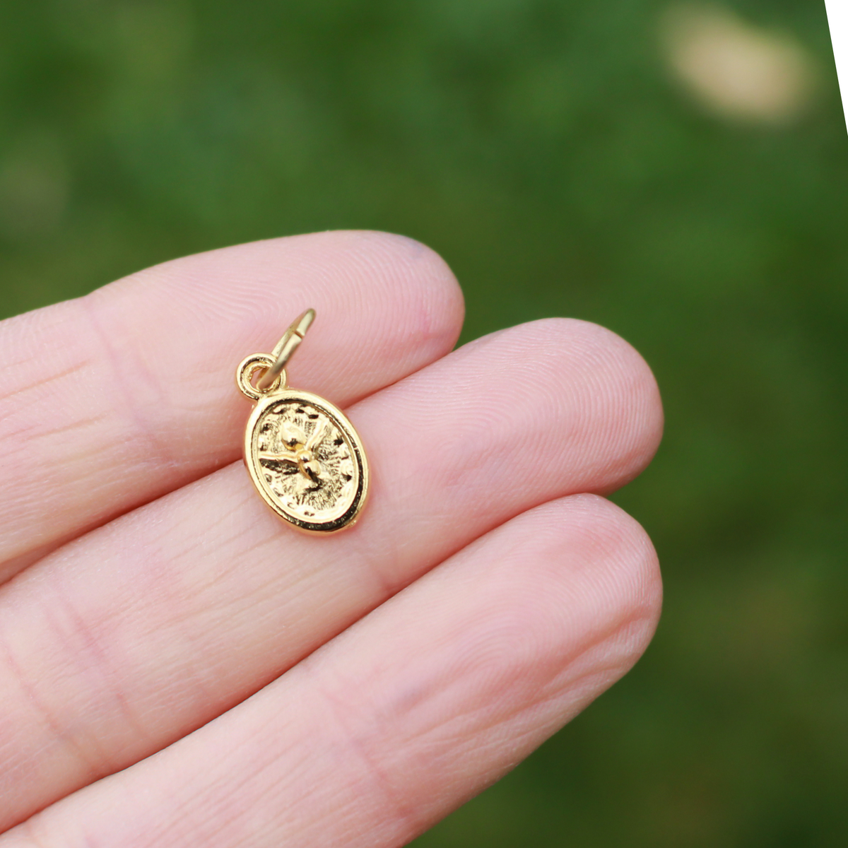 Miniature gold tone medal that depicts the Holy family of Joseph, Mary and Jesus on one side and the Holy Spirit dove depicted on the other sid