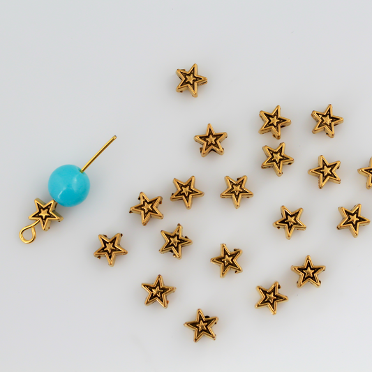 Tiny gold-tone metal beads shaped like five pointed stars, perfect for rosaries, chaplets, bracelets