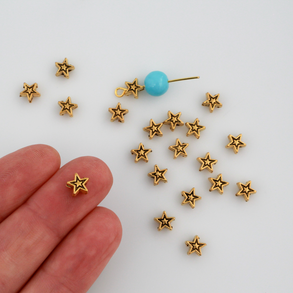Tiny gold-tone metal beads shaped like five pointed stars, perfect for rosaries, chaplets, bracelets