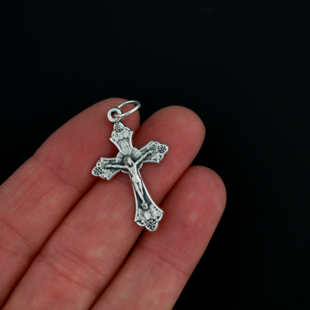 Small silver tone crucifix that features beautiful grape and leaf accents around the figure of Christ on the cross