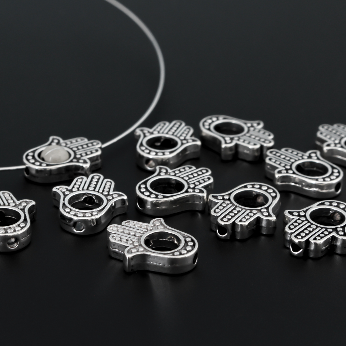 Hamsa hand bead frame crafted of zinc alloy and plated with an antiqued silver finish, it features a raised dot pattern on both sides and fits a 4mm round bead or smaller