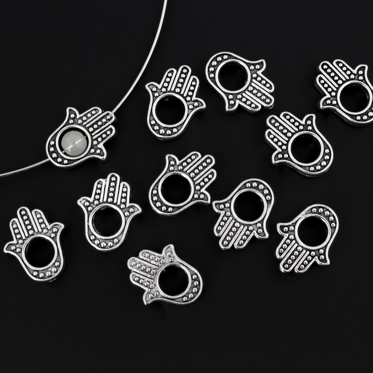 Hamsa hand bead frame crafted of zinc alloy and plated with an antiqued silver finish, it features a raised dot pattern on both sides and fits a 4mm round bead or smaller