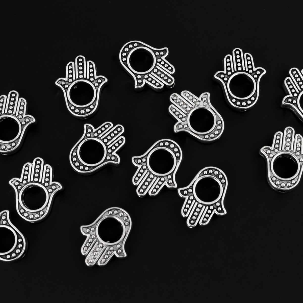 Hamsa hand bead frame crafted of zinc alloy and plated with an antiqued silver finish, it features a raised dot pattern on both sides and fits a 4mm round bead or smaller