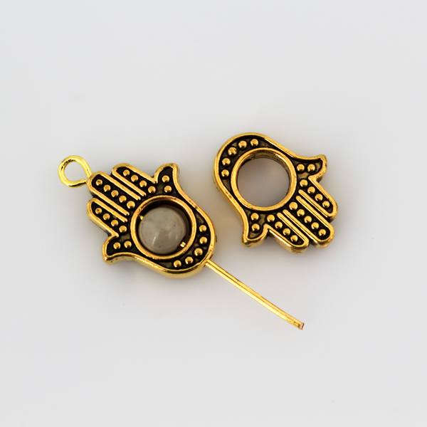 Hamsa hand bead frame crafted from zinc alloy and plated with an antiqued gold finish, it features a raised dot pattern on both sides and fits a 4mm round bead or smaller