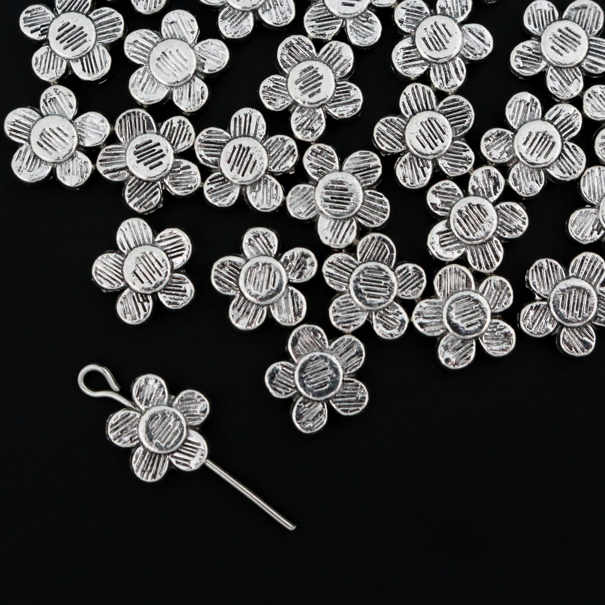 Antiqued silver-tone metal beads that are flat with a raised relief five petal flower pattern on both sides