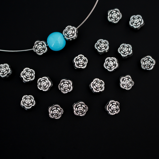 Antiqued silver-tone metal beads that are flat with a raised relief flower pattern on both sides, 6mm diameter by 4mm thick