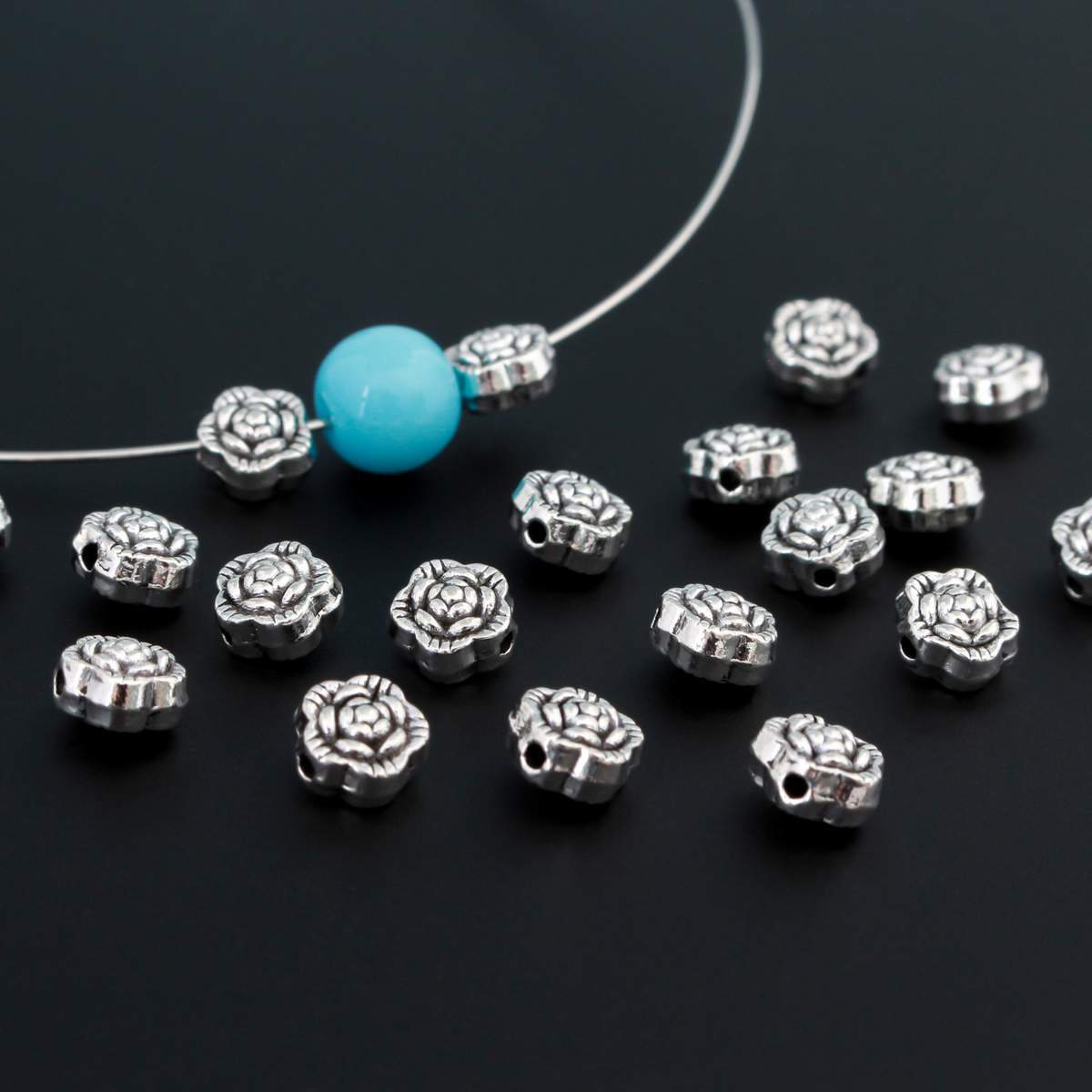 Antiqued silver-tone metal beads that are flat with a raised relief flower pattern on both sides, 6mm diameter by 4mm thick