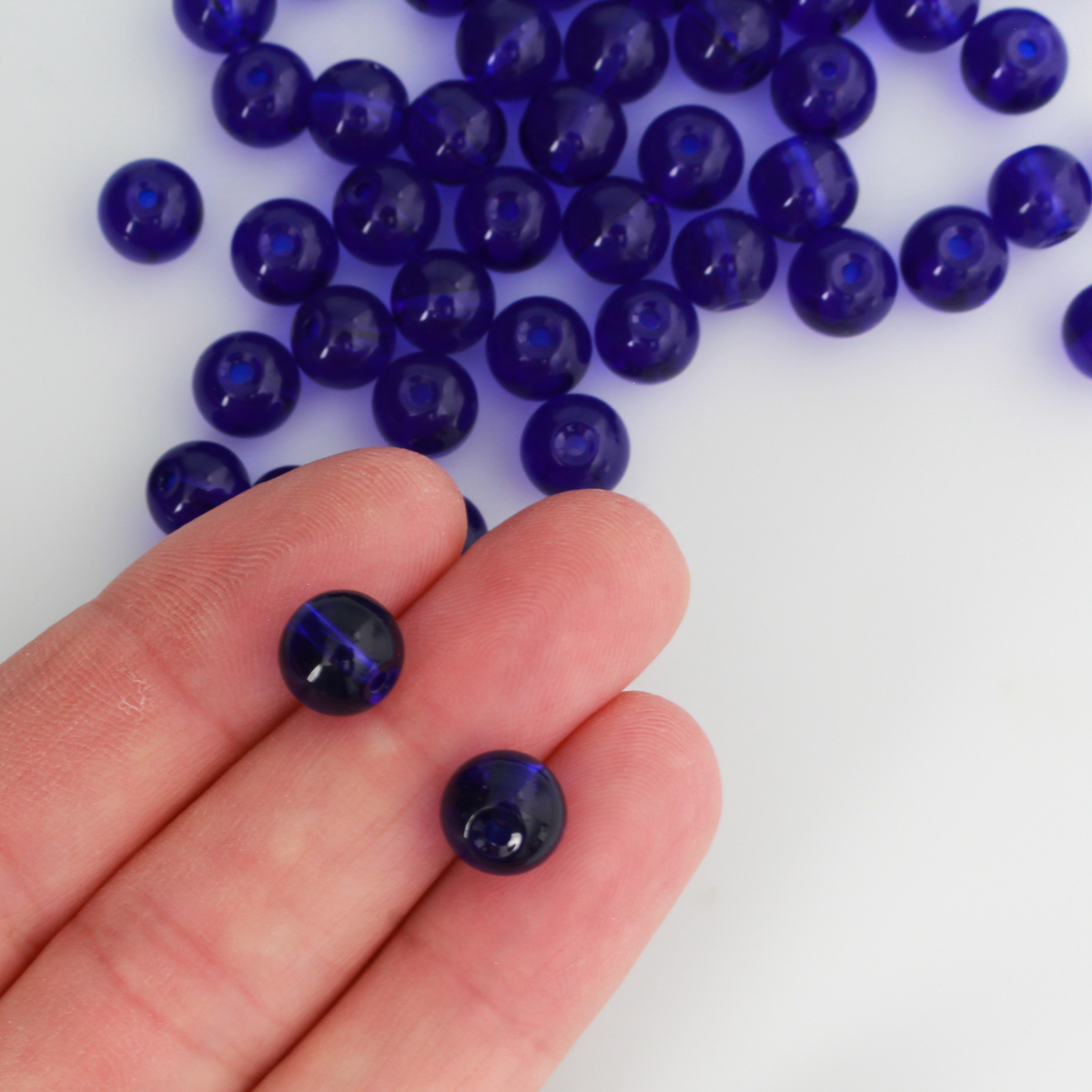 8mm round glass beads in a dark midnight blue color that is transparent.