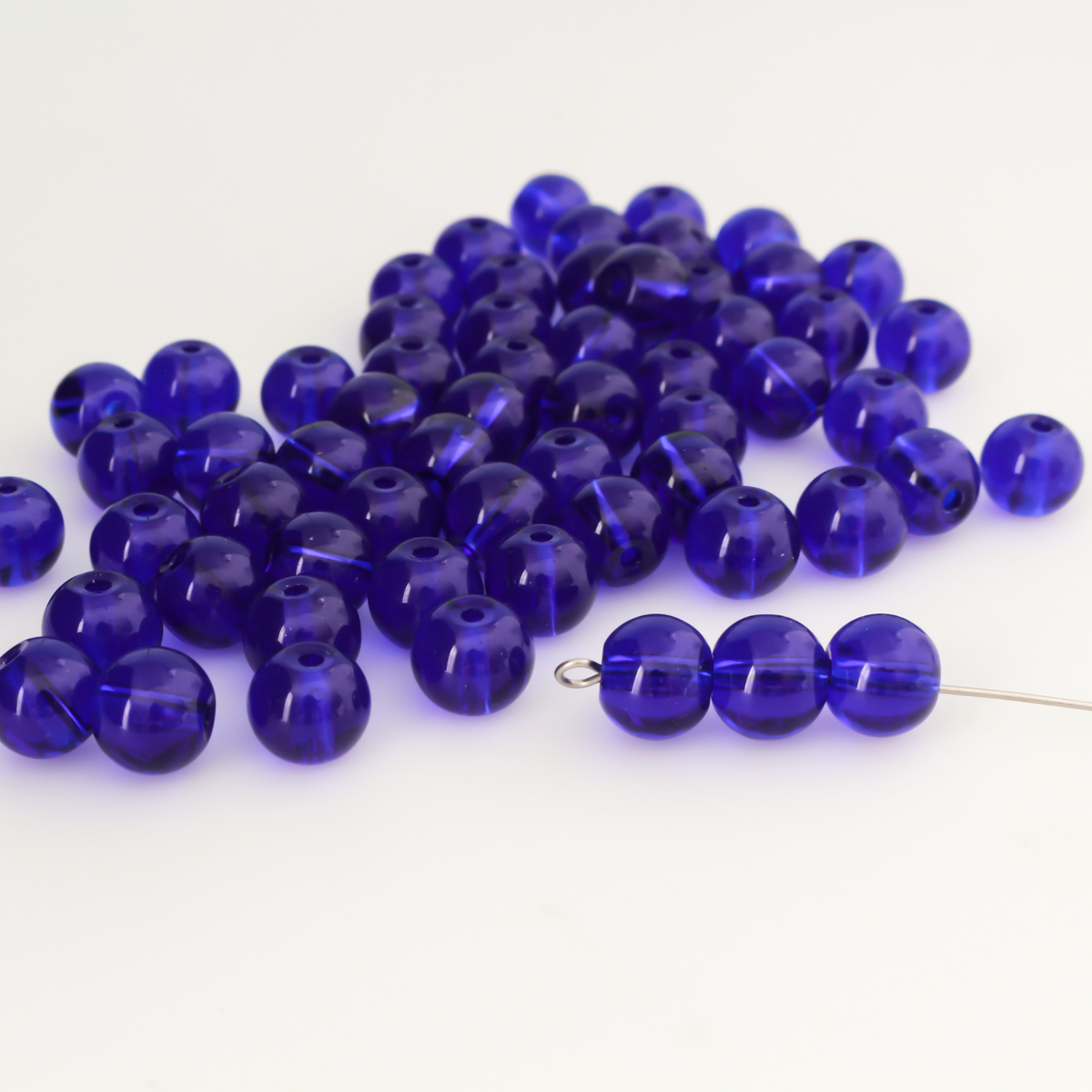 8mm round glass beads in a dark midnight blue color that is transparent.
