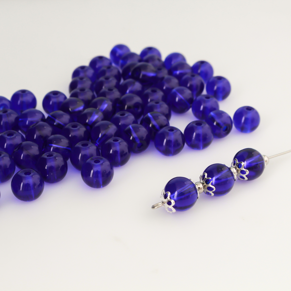 8mm round glass beads in a dark midnight blue color that is transparent.