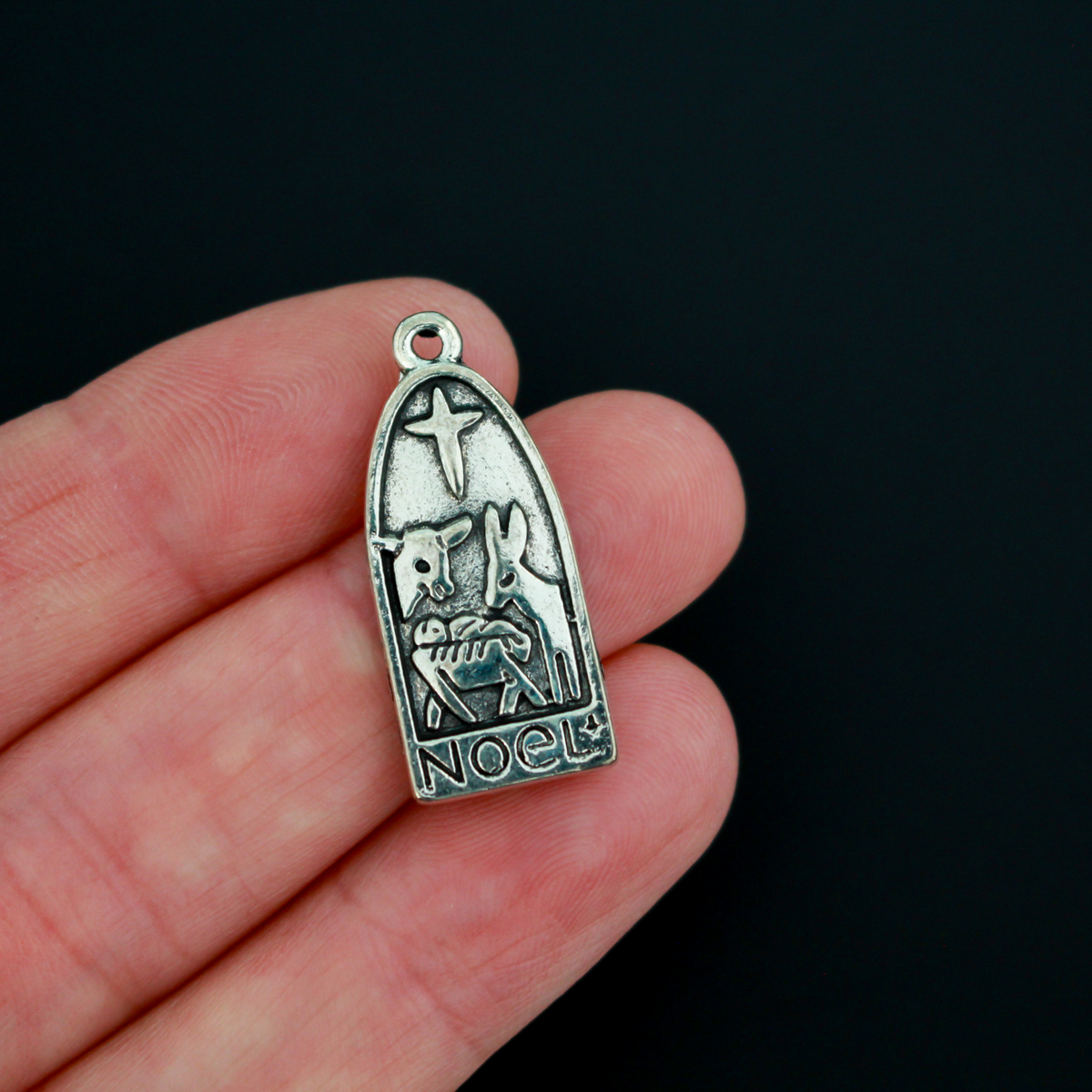 Arched charm depicting Christ child in the manger with the Christmas Star or the Star of Bethlehem above and a donkey and cow on either side