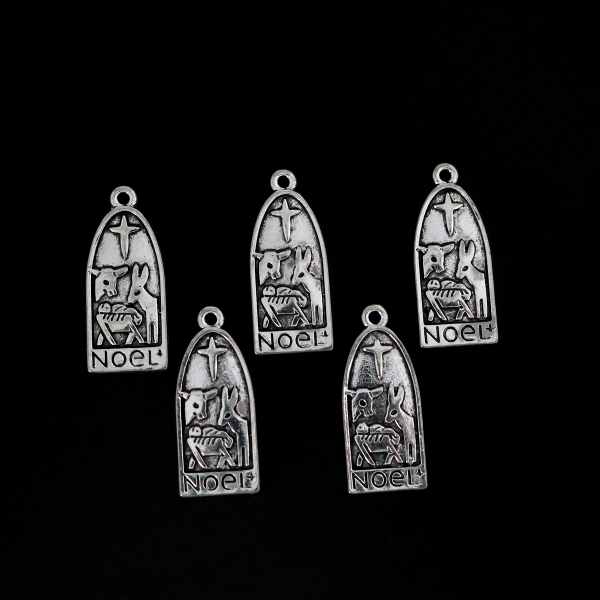 Arched charm depicting Christ child in the manger with the Christmas Star or the Star of Bethlehem above and a donkey and cow on either side