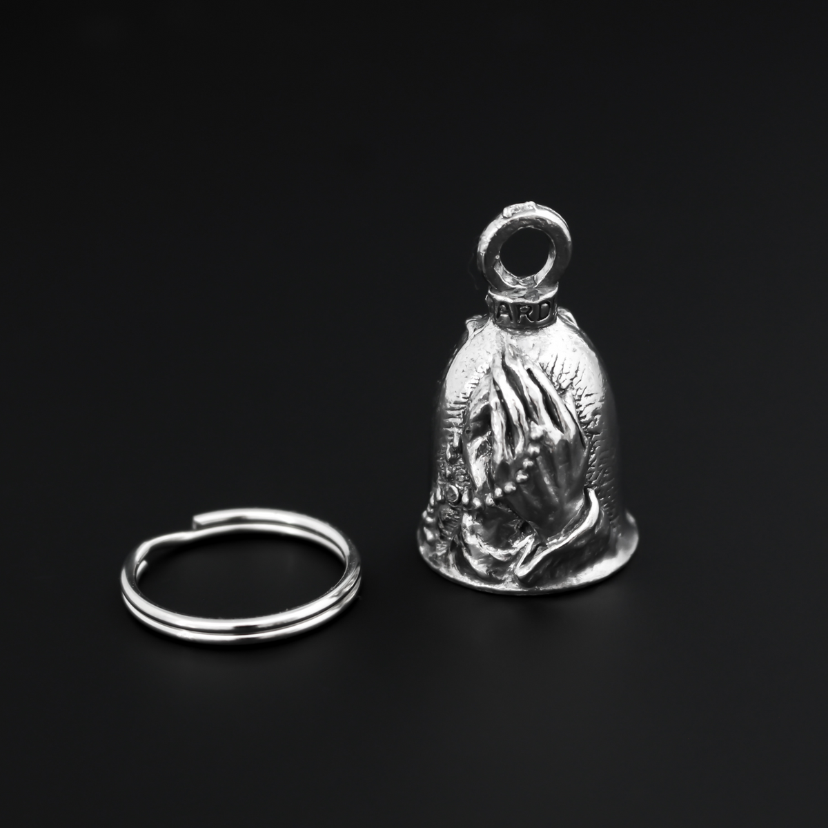 Praying hands Guardian bell. The front of the bell depicts a pair of hands in prayer holding a rosary. The rosary is also on the backside of the bell.