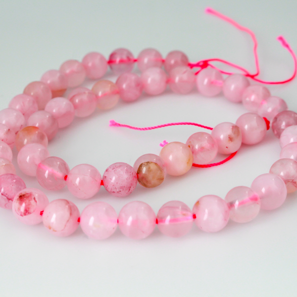 Natural rose quartz beads sold per strand. These are a soft muted pink color, some are transparent.