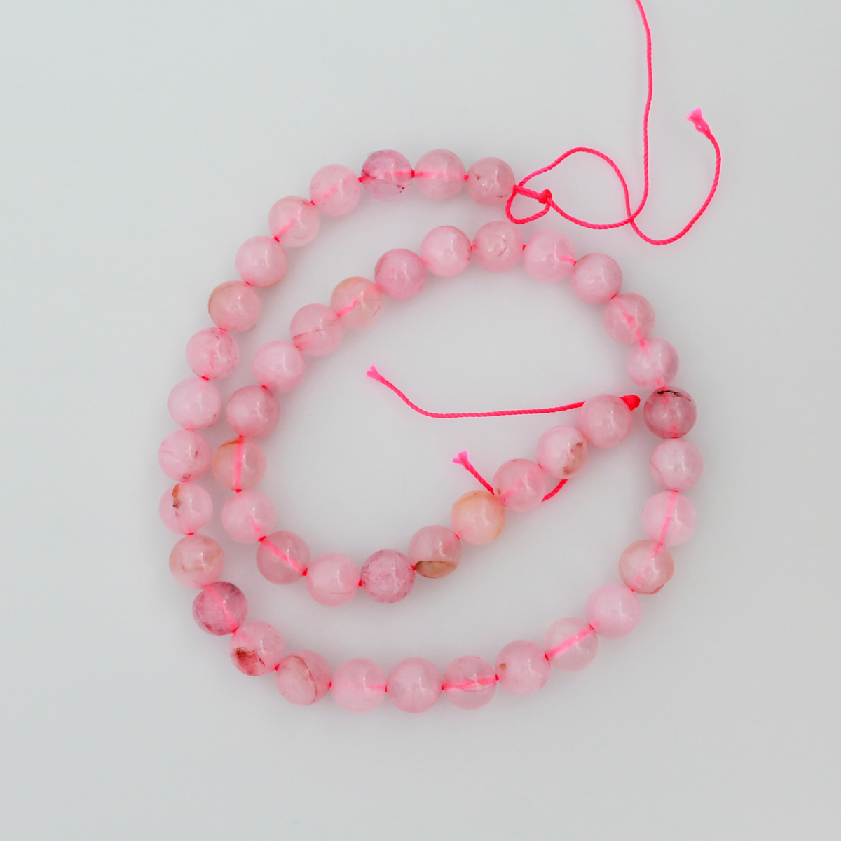 Natural rose quartz beads sold per strand. These are a soft muted pink color, some are transparent.