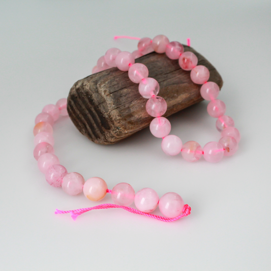 Natural rose quartz beads sold per strand. These are a soft muted pink color, some are transparent.