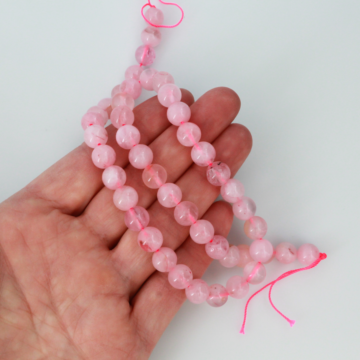 Natural rose quartz beads sold per strand. These are a soft muted pink color, some are transparent.