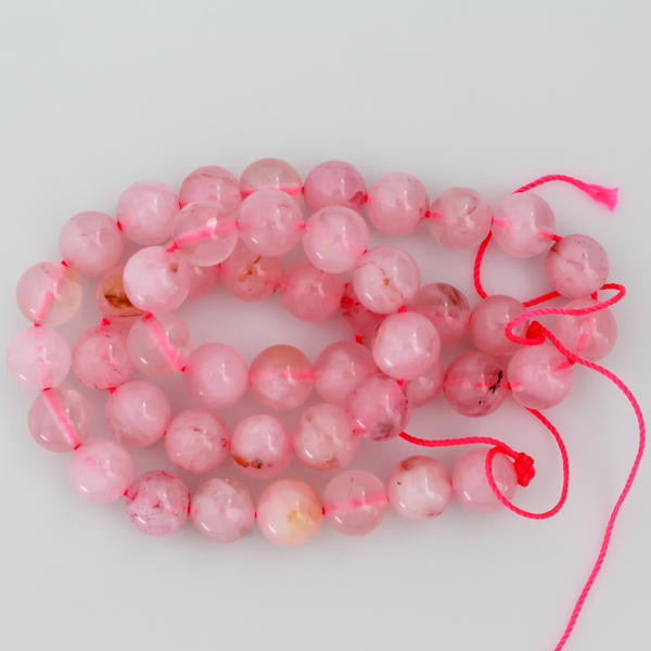 Natural rose quartz beads sold per strand. These are a soft muted pink color, some are transparent.