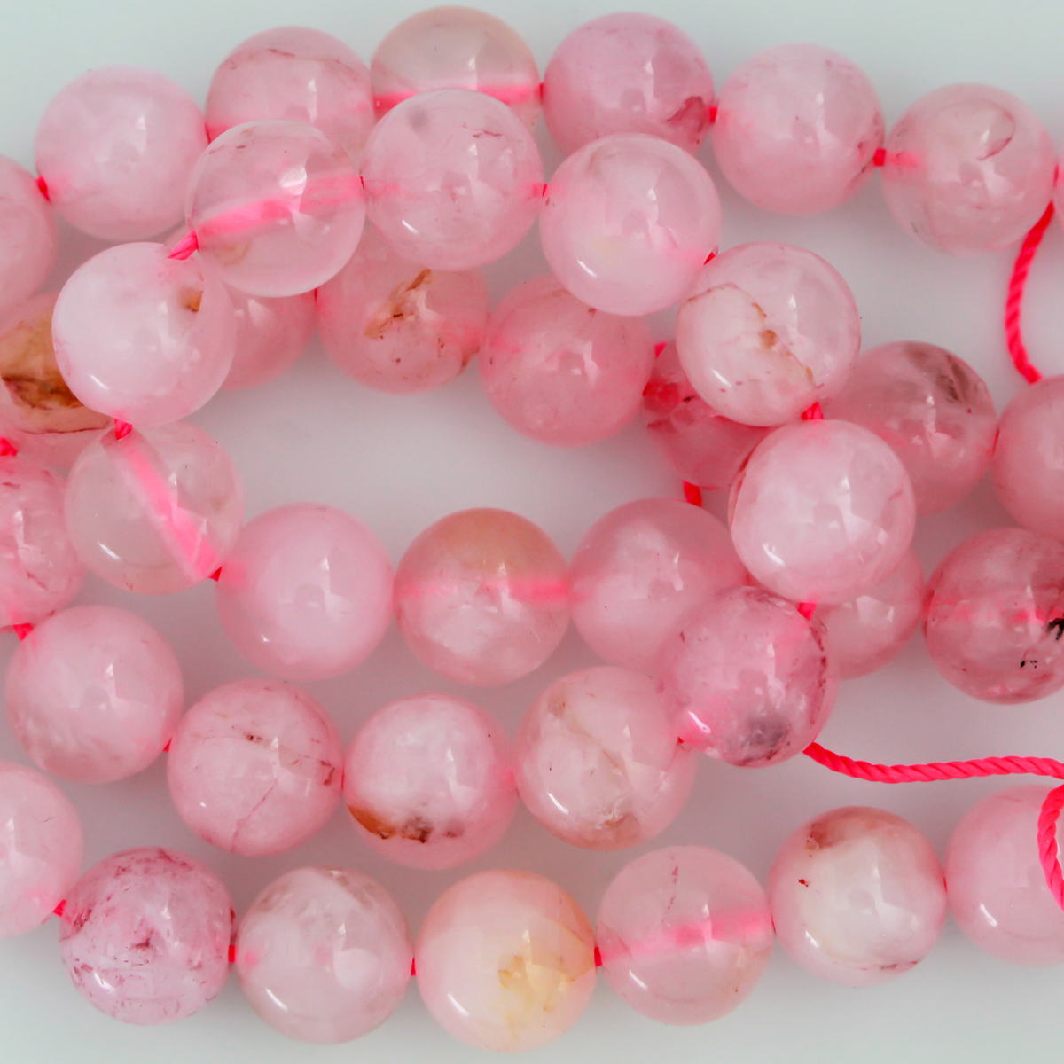 Natural rose quartz beads sold per strand. These are a soft muted pink color, some are transparent.