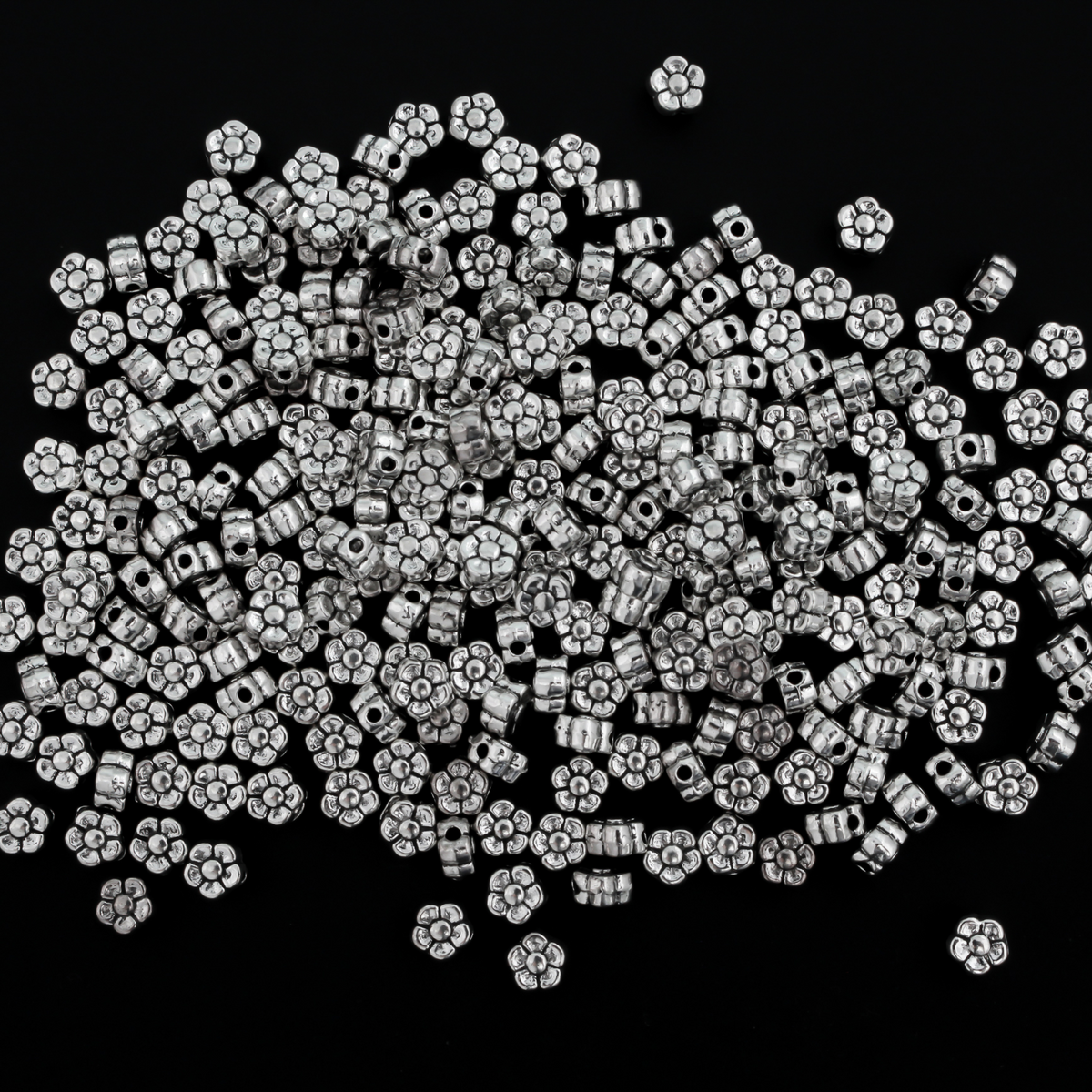 silver-tone metal beads that are flat with a raised relief five petal flower pattern on both sides