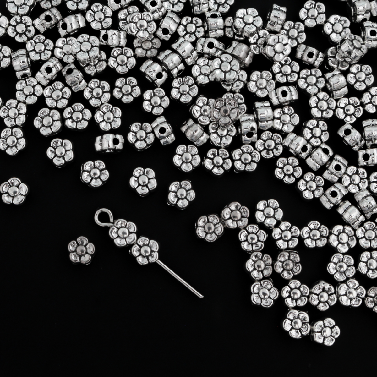 silver-tone metal beads that are flat with a raised relief five petal flower pattern on both sides
